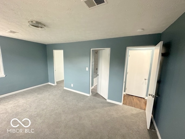 unfurnished bedroom featuring a textured ceiling and light colored carpet