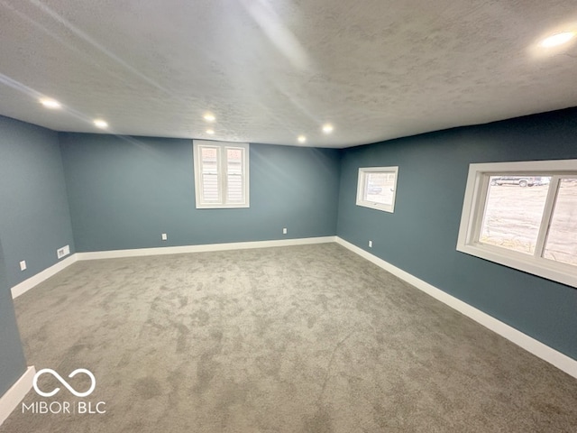 spare room featuring a wealth of natural light, carpet, and a textured ceiling