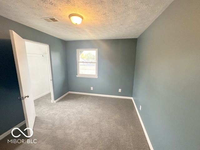 empty room featuring a textured ceiling and carpet flooring