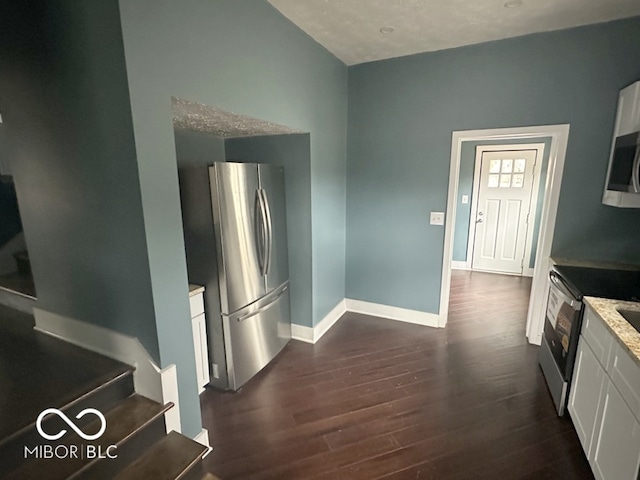 kitchen featuring light stone countertops, dark wood-type flooring, white cabinets, and stainless steel appliances