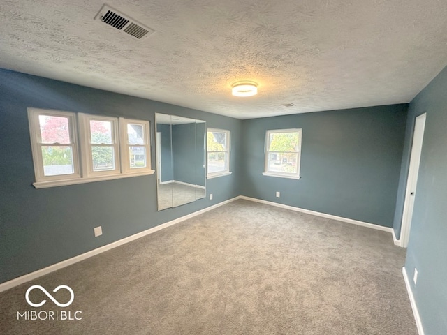 carpeted empty room featuring a textured ceiling