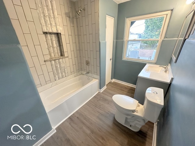 full bathroom featuring toilet, tiled shower / bath combo, vanity, and wood-type flooring