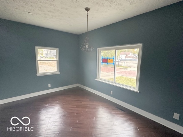 unfurnished room featuring dark wood-type flooring and a textured ceiling