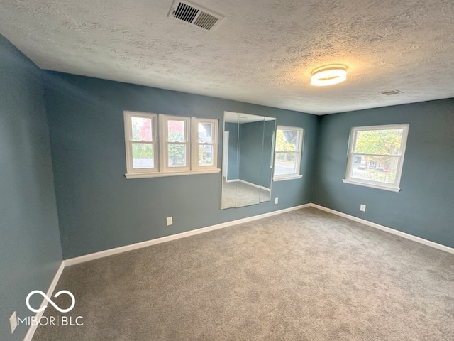 carpeted spare room with a textured ceiling