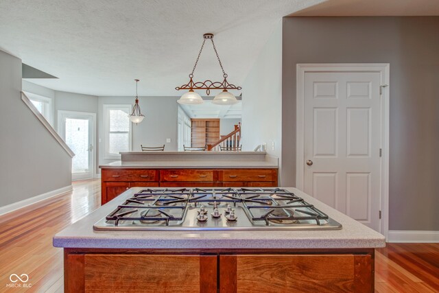 7189 Lockford N, Avon, IN 46123 - kitchen with stainless steel gas cooktop, brown cabinets, light wood finished floors, baseboards, and light countertops