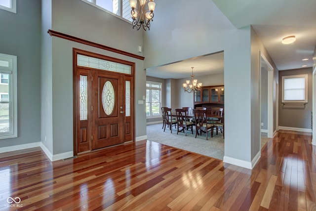 entrance foyer with a wealth of natural light, hardwood / wood-style floors, an inviting chandelier, and a high ceiling