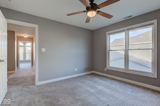 unfurnished room with light colored carpet, a healthy amount of sunlight, and ceiling fan