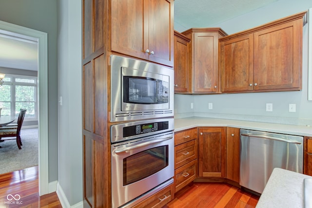 kitchen featuring a textured ceiling, appliances with stainless steel finishes, a notable chandelier, and wood-type flooring