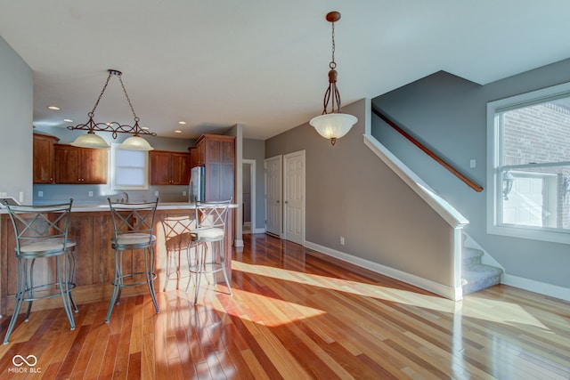 kitchen featuring light hardwood / wood-style flooring, kitchen peninsula, decorative light fixtures, and stainless steel fridge