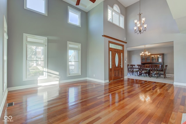 foyer entrance featuring a towering ceiling, ceiling fan with notable chandelier, and hardwood / wood-style floors