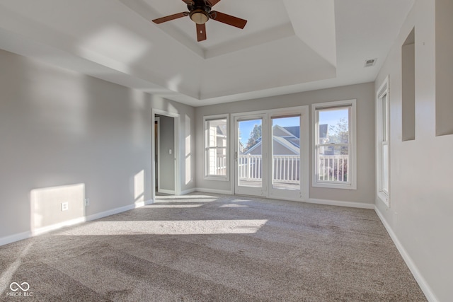 unfurnished room with light colored carpet, a tray ceiling, and ceiling fan