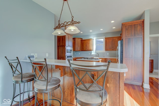 kitchen featuring a breakfast bar, stainless steel appliances, light hardwood / wood-style flooring, and pendant lighting