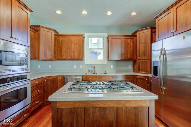 kitchen with sink, a center island, stainless steel appliances, and hardwood / wood-style flooring