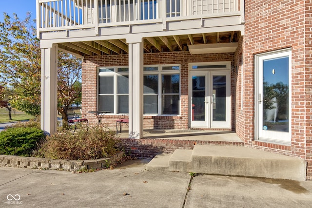 view of exterior entry with french doors and a balcony