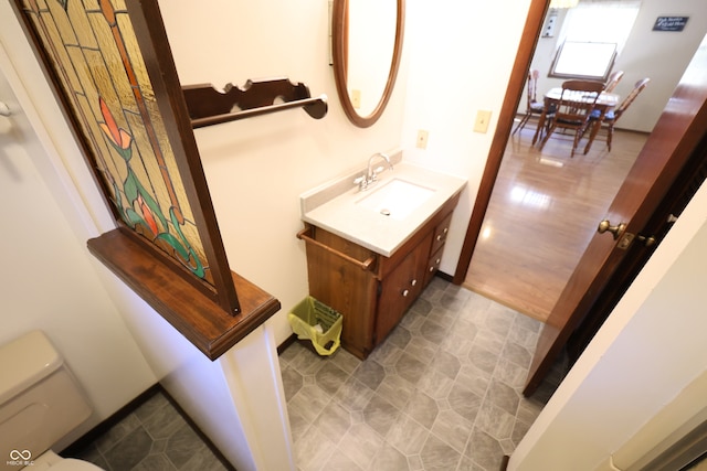 bathroom with toilet, vanity, and wood-type flooring