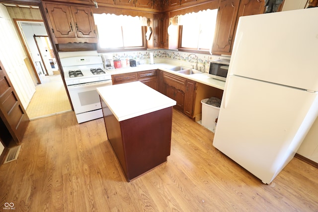 kitchen with white appliances, sink, light hardwood / wood-style floors, and a center island