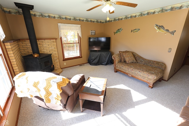 carpeted living room with a wood stove and ceiling fan