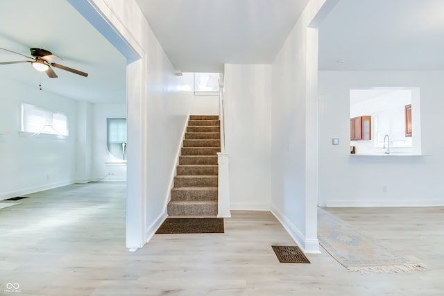 stairway with ceiling fan and hardwood / wood-style flooring