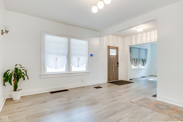 foyer with beam ceiling and light wood-type flooring