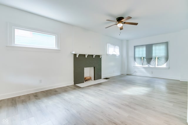 unfurnished living room featuring light hardwood / wood-style flooring, ceiling fan, plenty of natural light, and a brick fireplace