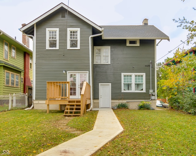 rear view of house featuring a wooden deck and a lawn