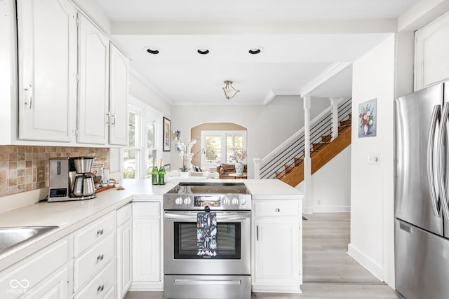 kitchen featuring decorative backsplash, light hardwood / wood-style flooring, kitchen peninsula, stainless steel appliances, and white cabinets