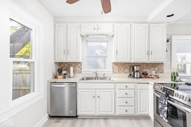 kitchen with stainless steel appliances, sink, white cabinets, light hardwood / wood-style floors, and tasteful backsplash