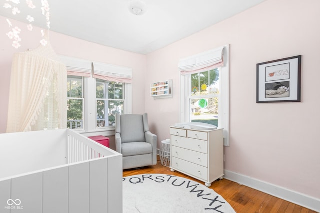 bedroom featuring light hardwood / wood-style floors, multiple windows, and a crib