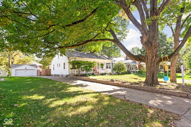 view of front of home featuring a garage, a front lawn, and an outbuilding