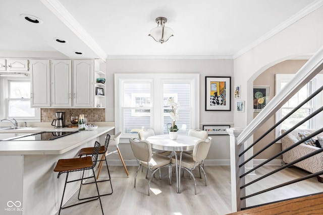 dining space with ornamental molding and light wood-type flooring