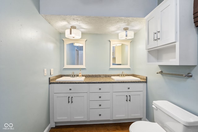 bathroom with toilet, a textured ceiling, vanity, and hardwood / wood-style floors