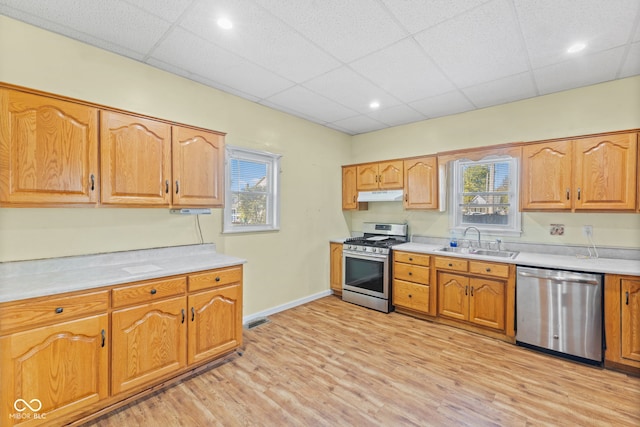 kitchen featuring sink, a drop ceiling, stainless steel appliances, and light hardwood / wood-style floors