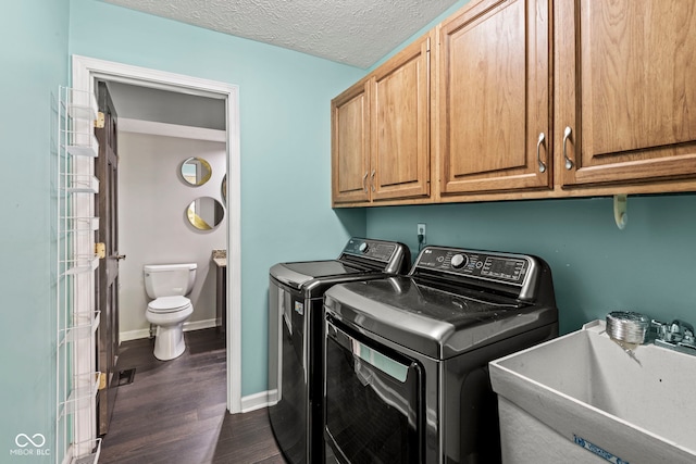 laundry area featuring independent washer and dryer, a textured ceiling, sink, and dark hardwood / wood-style flooring