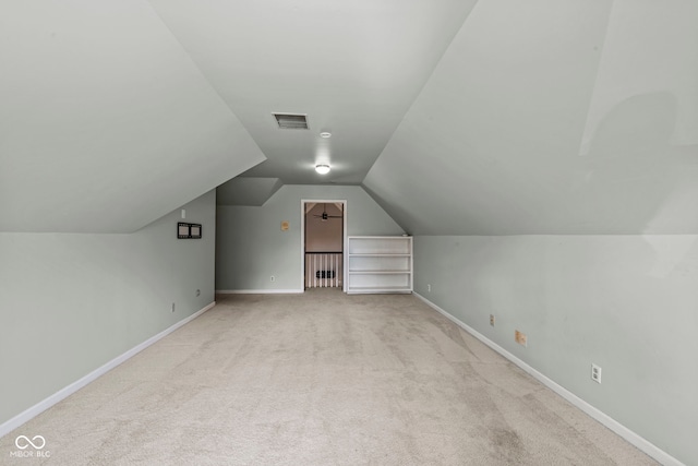 bonus room with lofted ceiling and light colored carpet