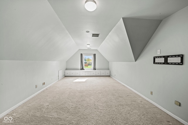 additional living space featuring vaulted ceiling and light carpet