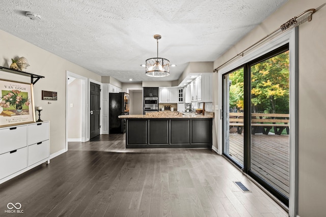 kitchen featuring black refrigerator, a chandelier, white cabinetry, light stone counters, and dark hardwood / wood-style flooring