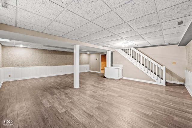 basement with a drop ceiling and wood-type flooring