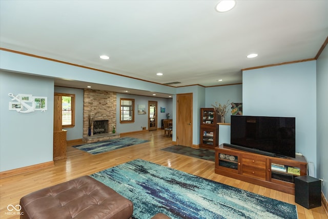 living room with crown molding, a stone fireplace, and wood-type flooring