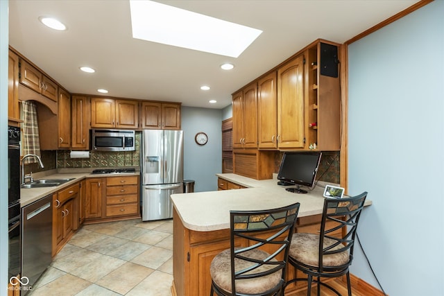 kitchen with appliances with stainless steel finishes, a kitchen bar, backsplash, and kitchen peninsula