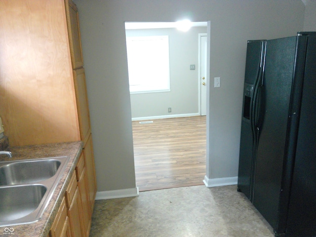 kitchen featuring sink, light wood-type flooring, and black fridge with ice dispenser