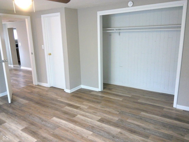 unfurnished bedroom with hardwood / wood-style floors, a closet, and ceiling fan