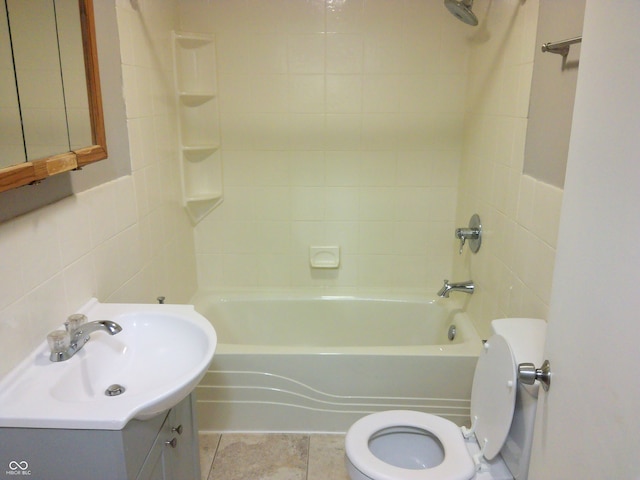 full bathroom with tile walls, toilet, vanity, tiled shower / bath combo, and tile patterned flooring