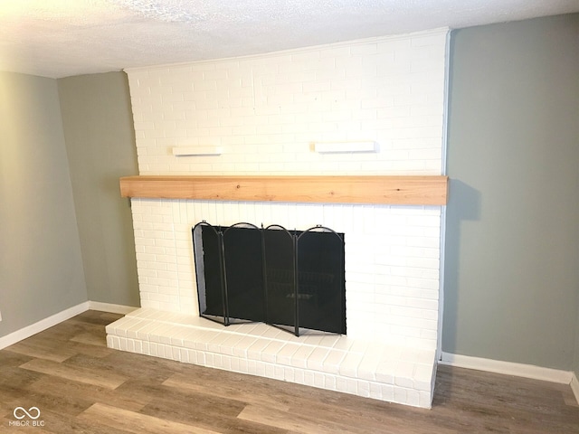 room details with a brick fireplace, hardwood / wood-style flooring, and a textured ceiling