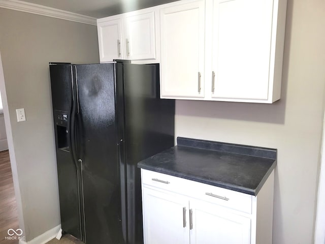 kitchen with black fridge, crown molding, and white cabinets