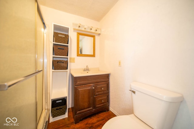 bathroom with vanity, toilet, hardwood / wood-style flooring, and vaulted ceiling