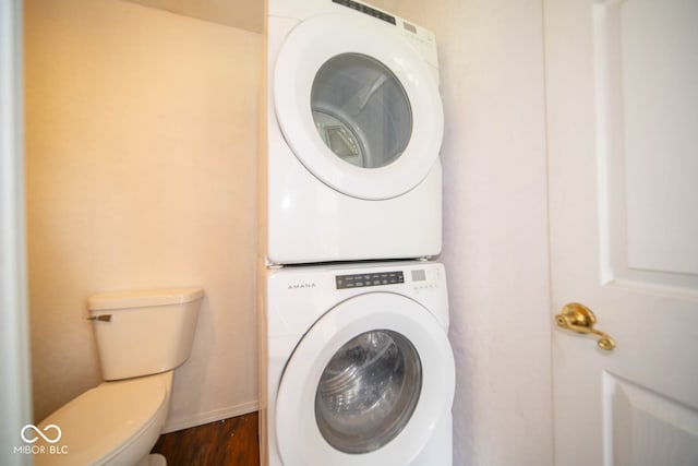 laundry room featuring stacked washer and dryer and dark hardwood / wood-style flooring