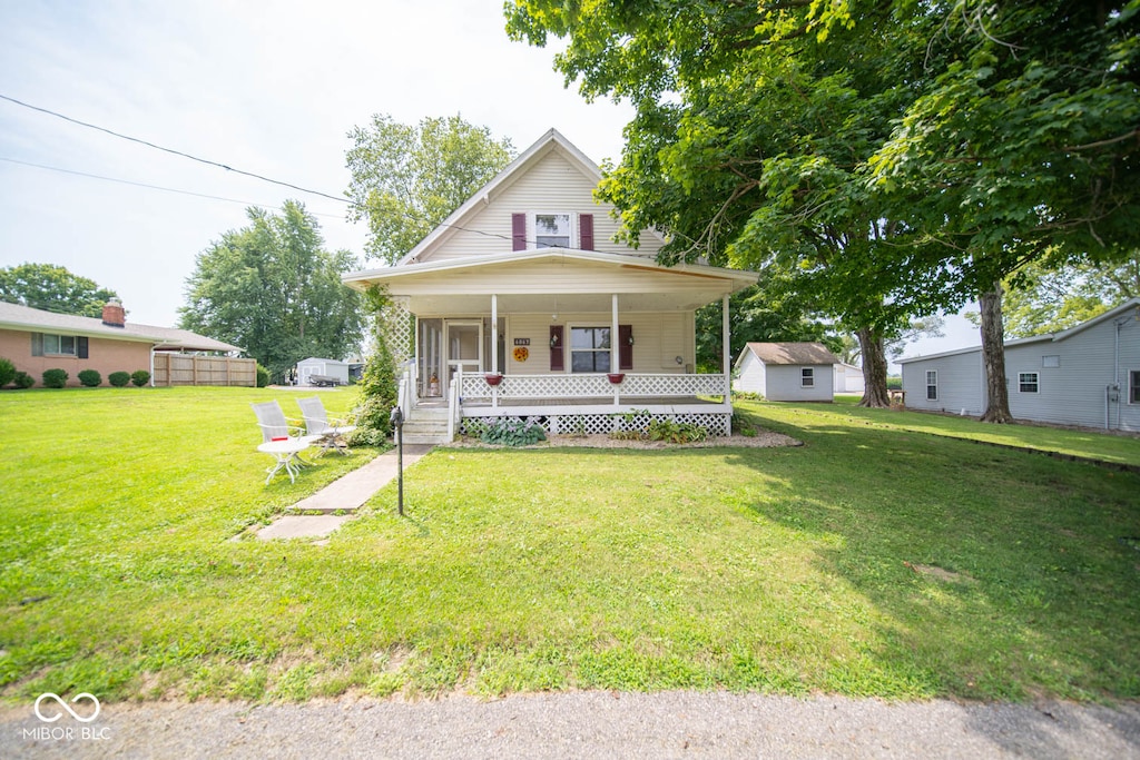 country-style home with a front lawn, an outbuilding, and a porch