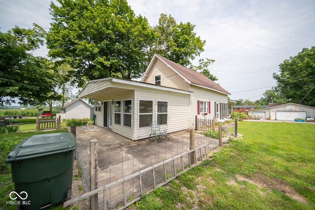 rear view of property featuring a yard, an outbuilding, and a garage