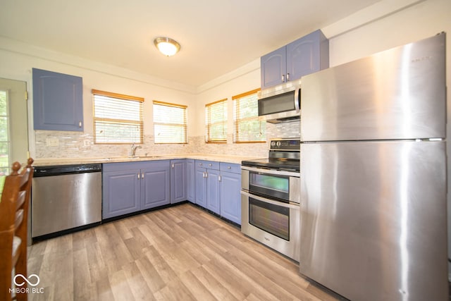 kitchen featuring tasteful backsplash, appliances with stainless steel finishes, light hardwood / wood-style flooring, ornamental molding, and sink