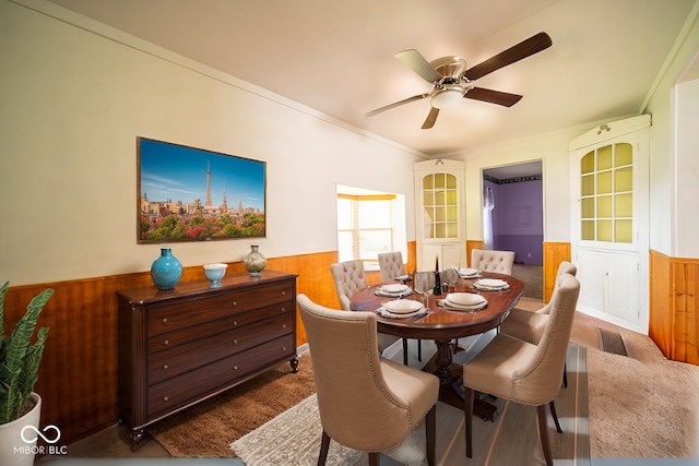 dining area featuring crown molding, wooden walls, and ceiling fan